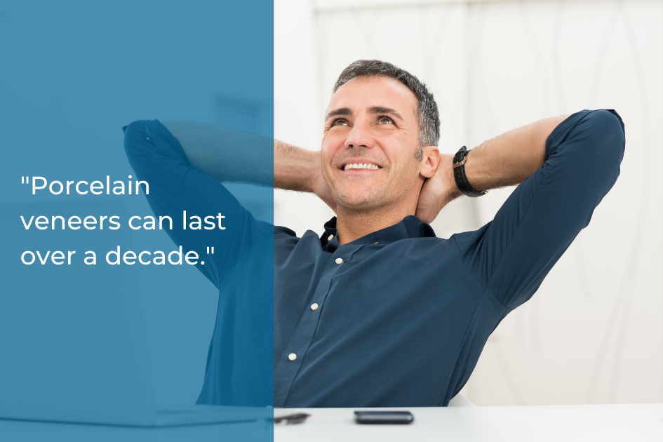 A man in a blue shirt sits relaxed at a desk, smiling confidently, as text on the image reads, "Porcelain veneers can last over a decade and are an ideal solution for stained teeth.