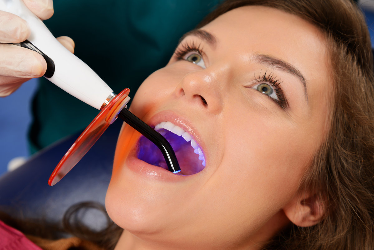Young woman patient stopping treatment with dental UV light equipment