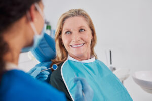 Smiling senior woman looking at dentist during tooth replacement consultation