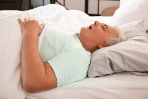 Person sleeping while partner lies awake concerned about snoring and sleep apnea